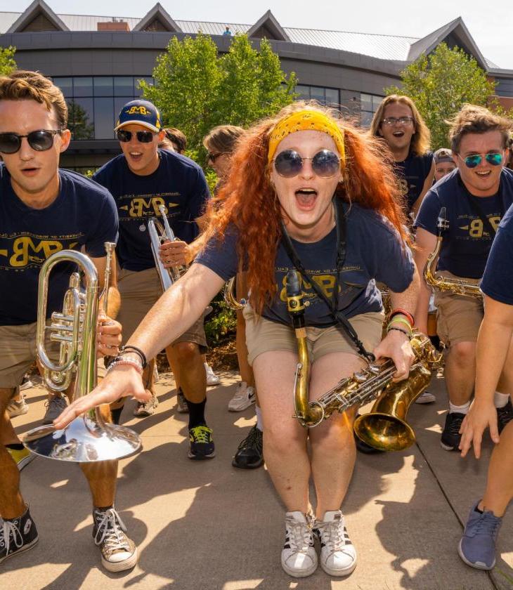 Members of the marching band cheer and pose for a photo with their instruments and matching t-shirts